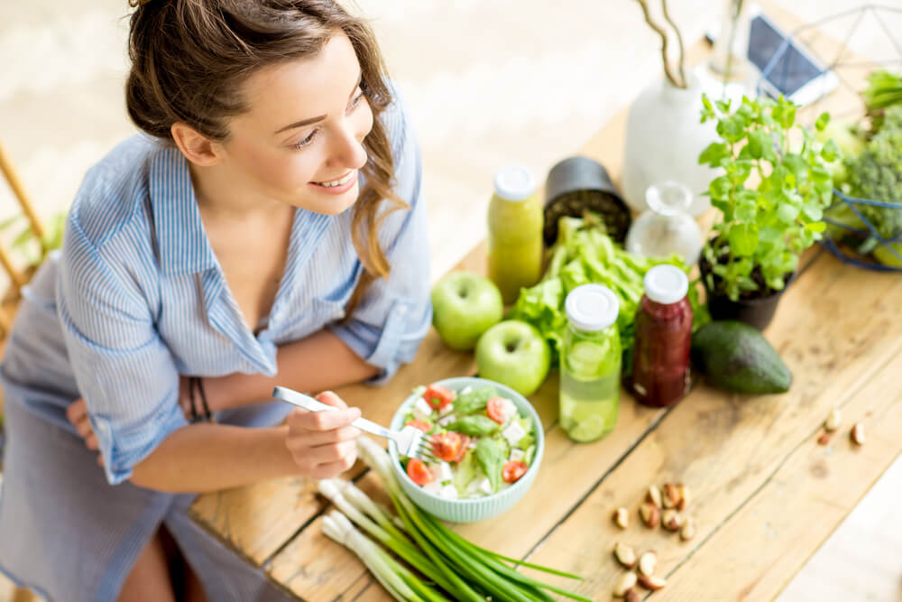 Žena s úsměvem jí zdravý zeleninový salát